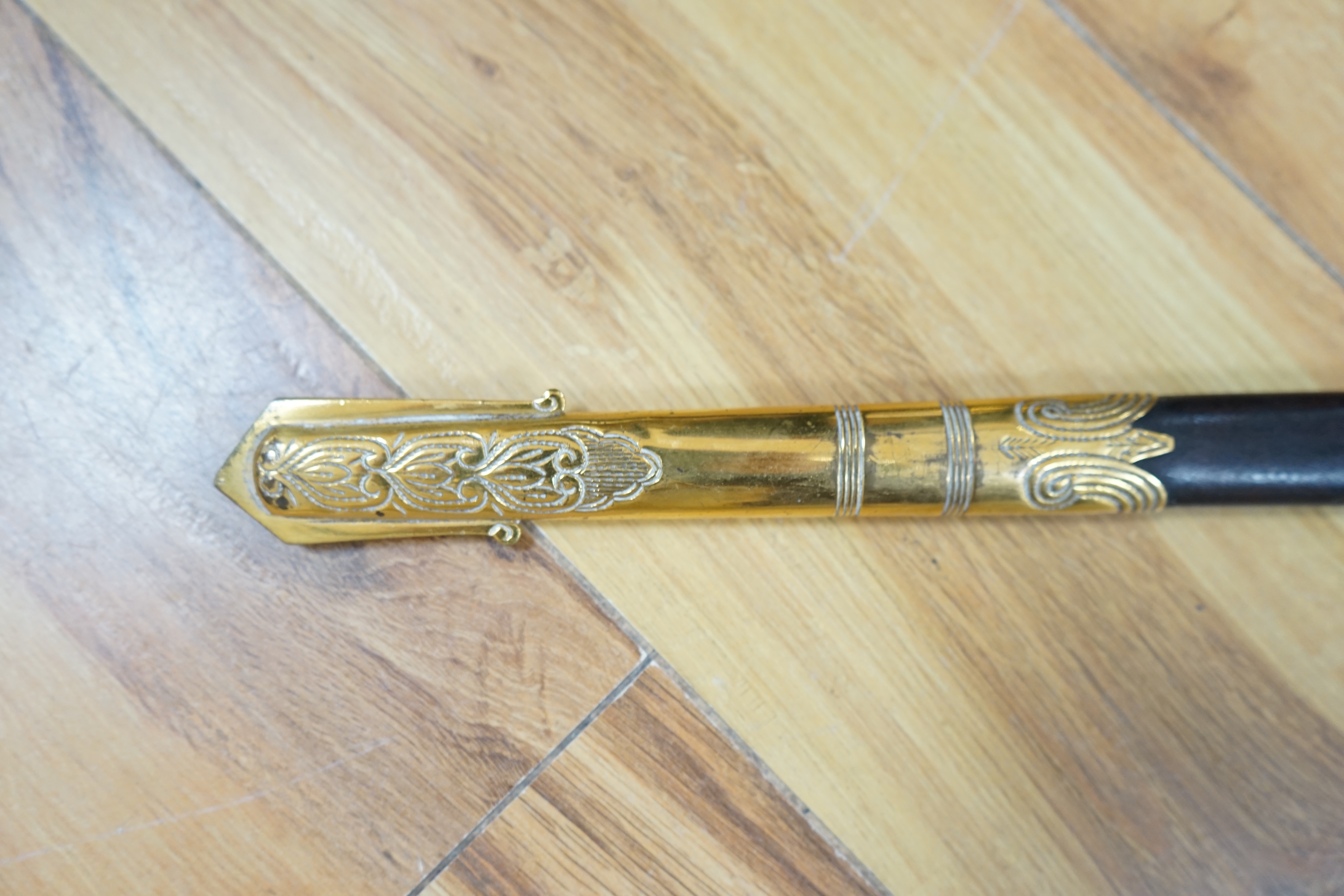 A Victorian Royal Navy officer’s sword by Grieves, engraved blade, lion’s head pommel, fish skin grip, folding guard engraved with R.J. Murray, with its sword knot and leather scabbard with brass mounts, blade 79cm. Cond